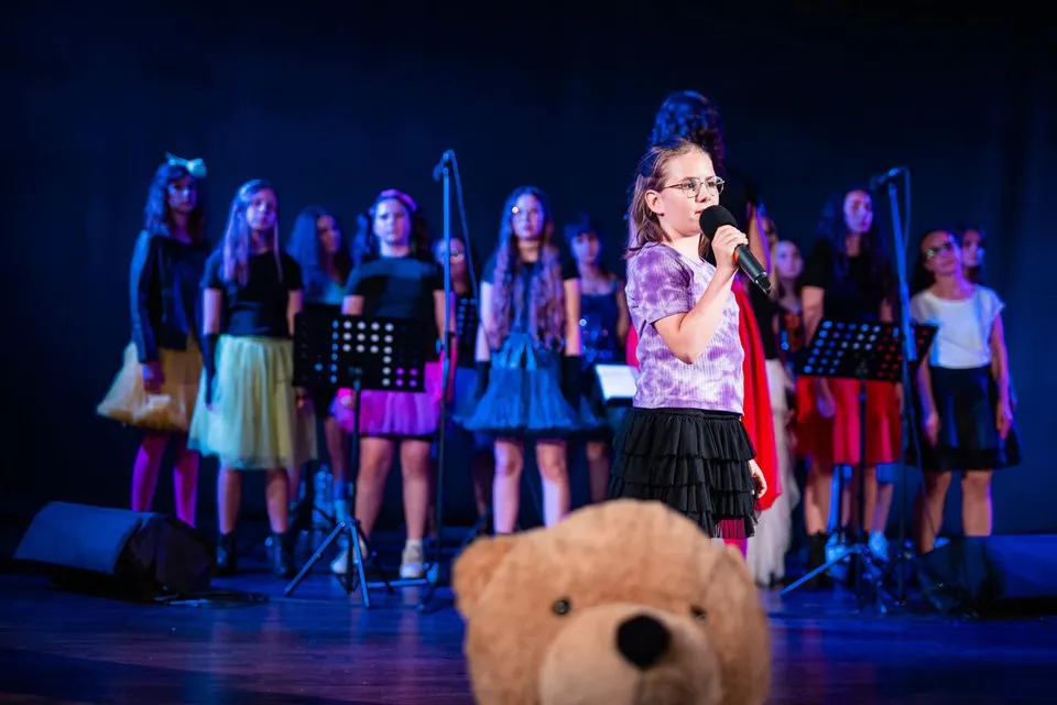Uczestniczki koncertu VocaLove śpiewają wspólnie na oświetlonej scenie
